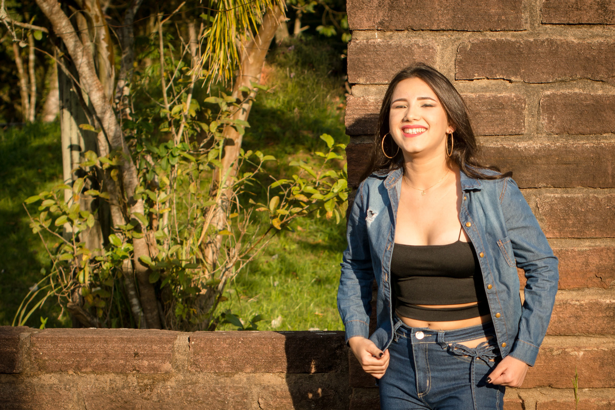Ensaio feminino, sorriso espontâneo com muro de pedra