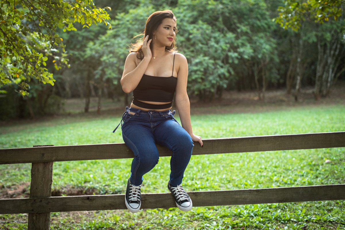 Ensaio feminino sentada numa cerca de madeira no Pareci Novo