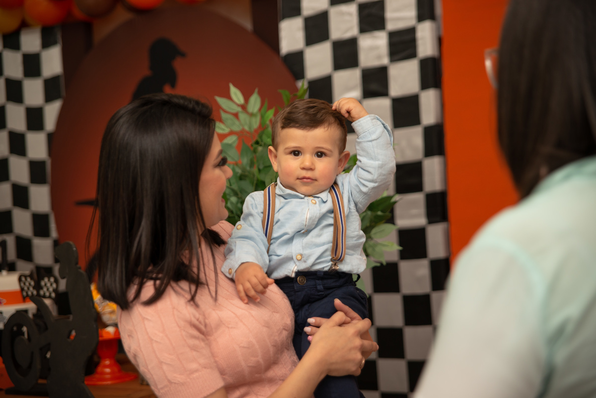 Menino na festa de um aninho no colo da mãe
