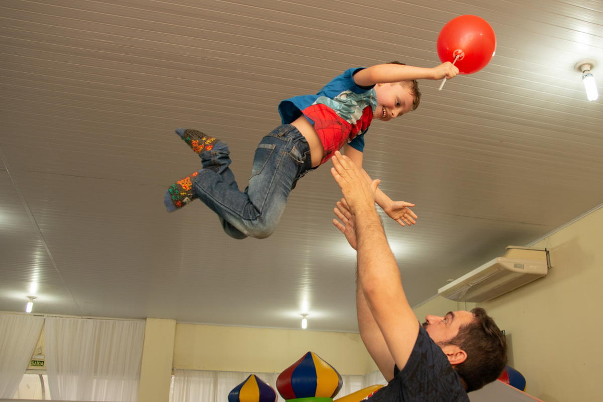pai jogando filho para cima em festa infantil em casa de festa em Montenegro