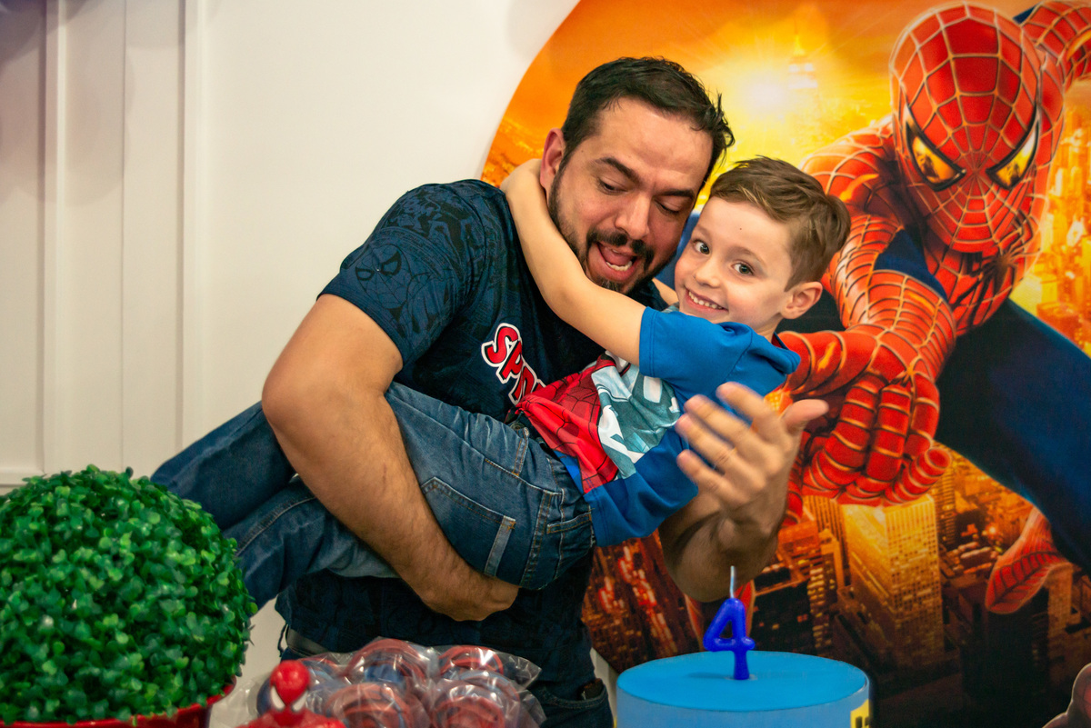 Pai e filho junto à decoração de festa infantil do homem aranha