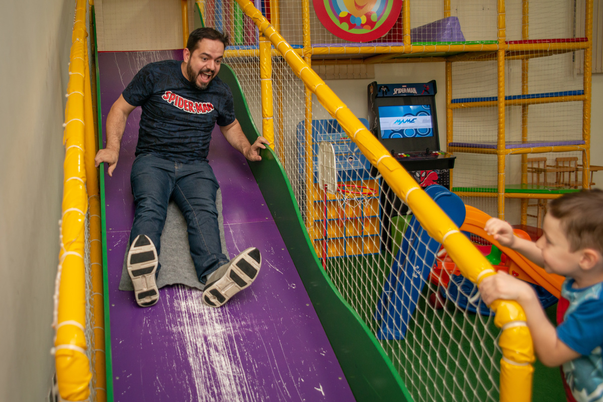 Pai brincando no escorregador de festa infantil em Montenegro