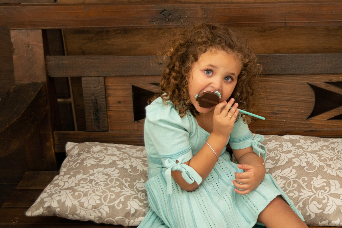 menina comendo doce de chocolate em casa de festa infantil em Montenegro RS
