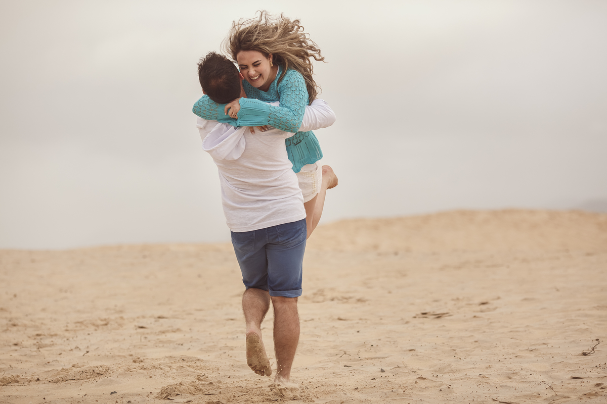 casal se abraçando em dunas de areia