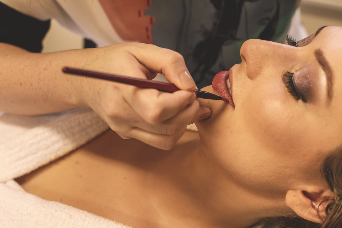 maquiadora passando batom na boca da noiva