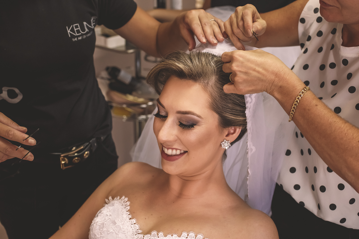 detalhe de cabeleireira colocando véu de noiva