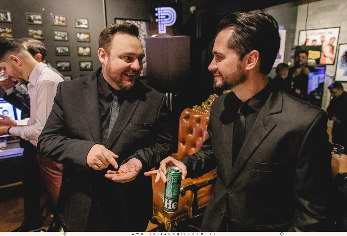 padrinho segurando comprimidos conversando com outro padrinho que está segurando uma cerveja