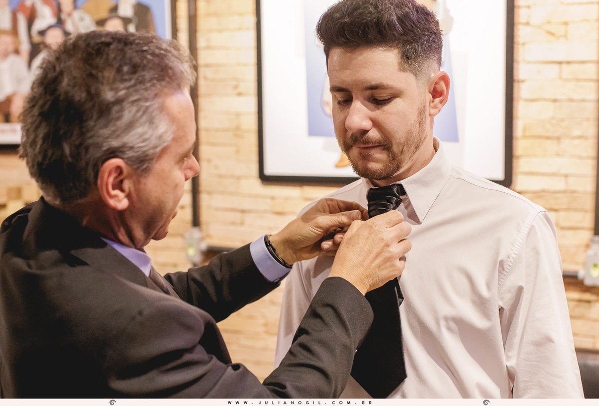 pai do noivo ajustando a gravata no filho