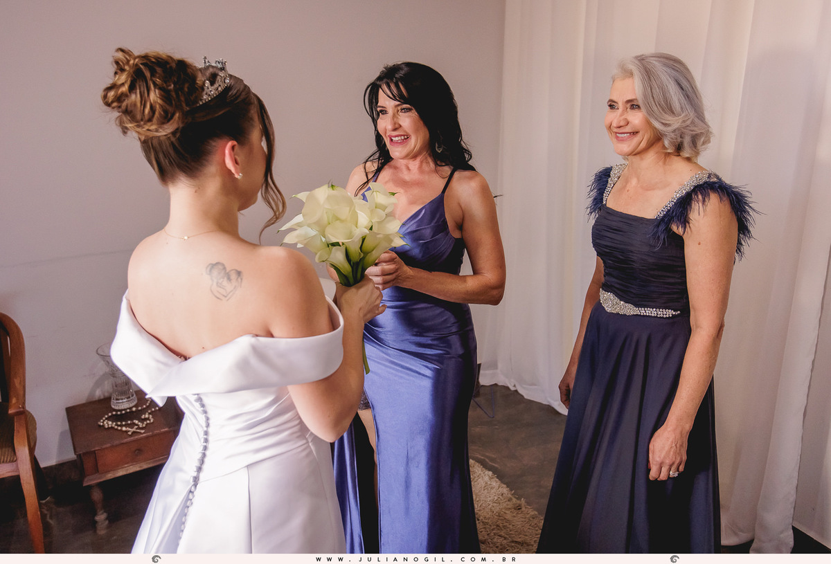 mãe e sogra da noiva vendo ela pronta