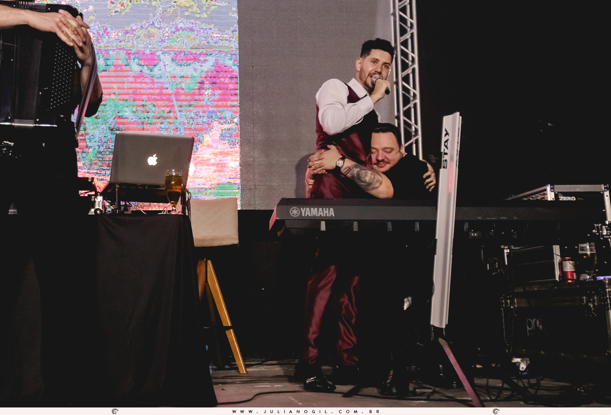 noivo sendo abraçado por padrinho no palco