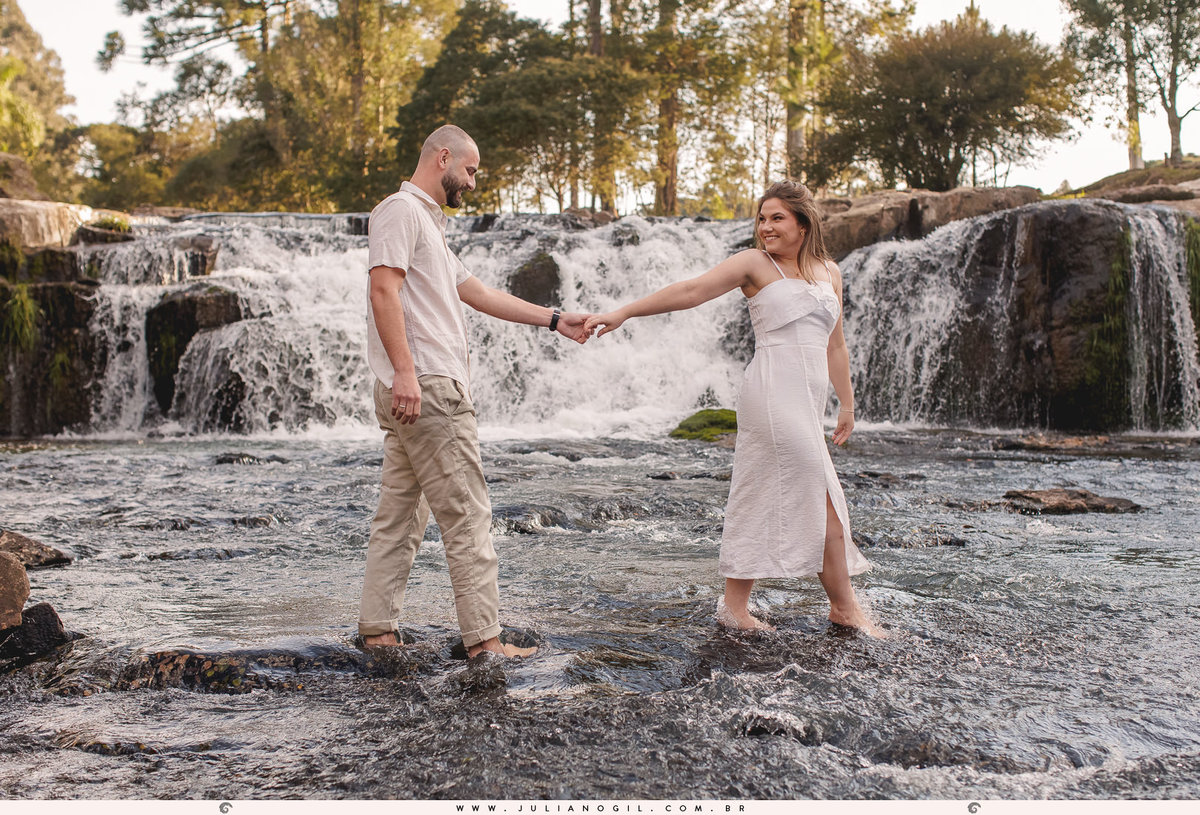 casal andando na água ao fundo a cachoeira Dusanoski