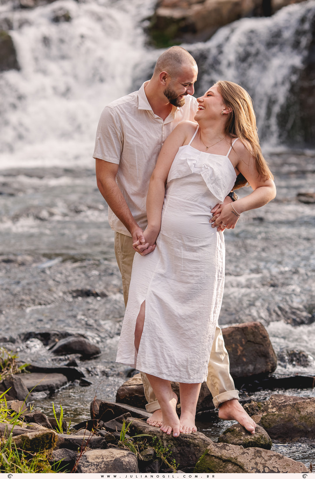 casal andando na água ao fundo a cachoeira