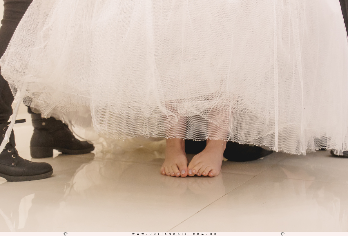 pés da noiva adriele enquanto está sendo auxiliada por outras pessoas ao colocar o vestido