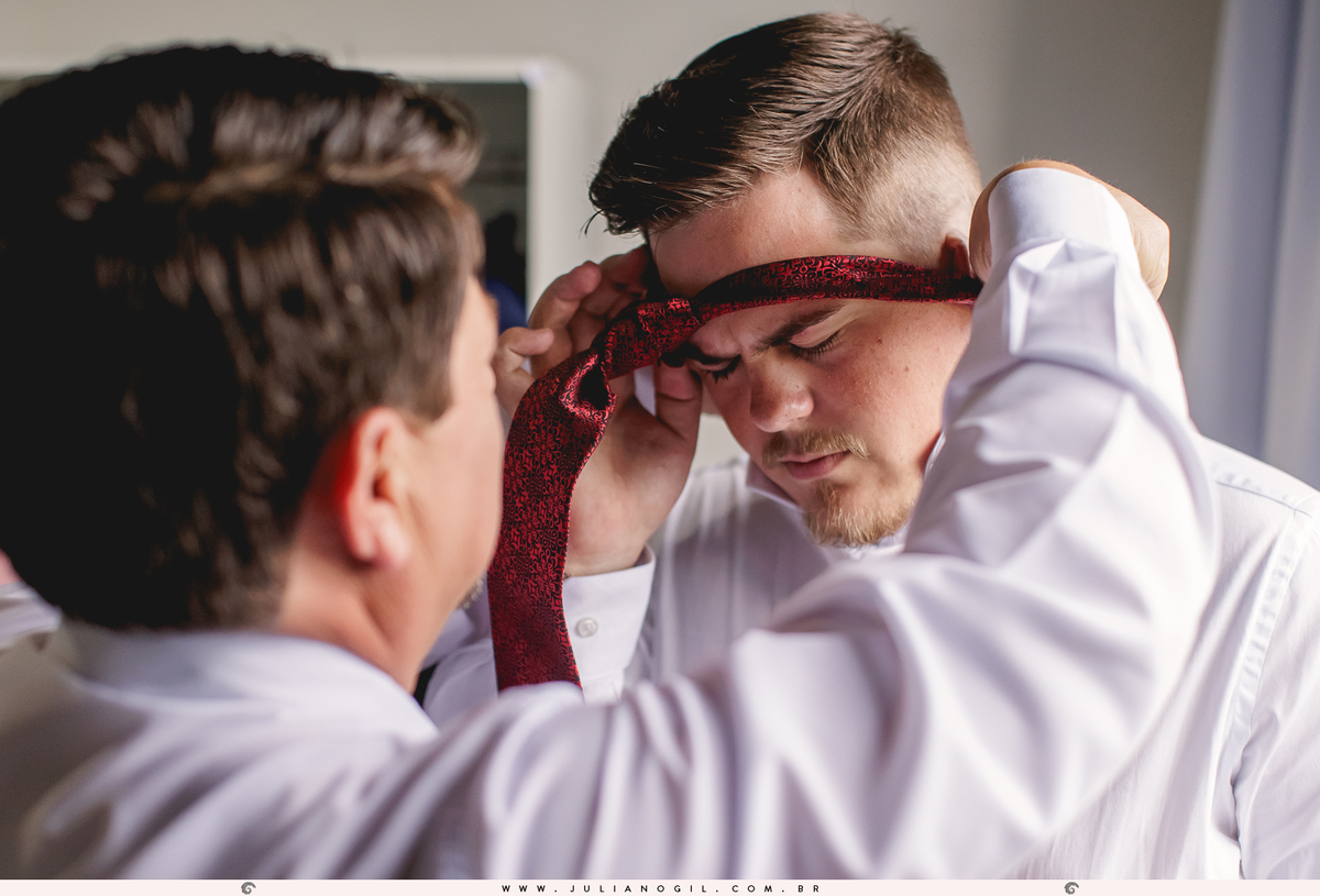 pai do noivo aldo colocando a gravata no filho