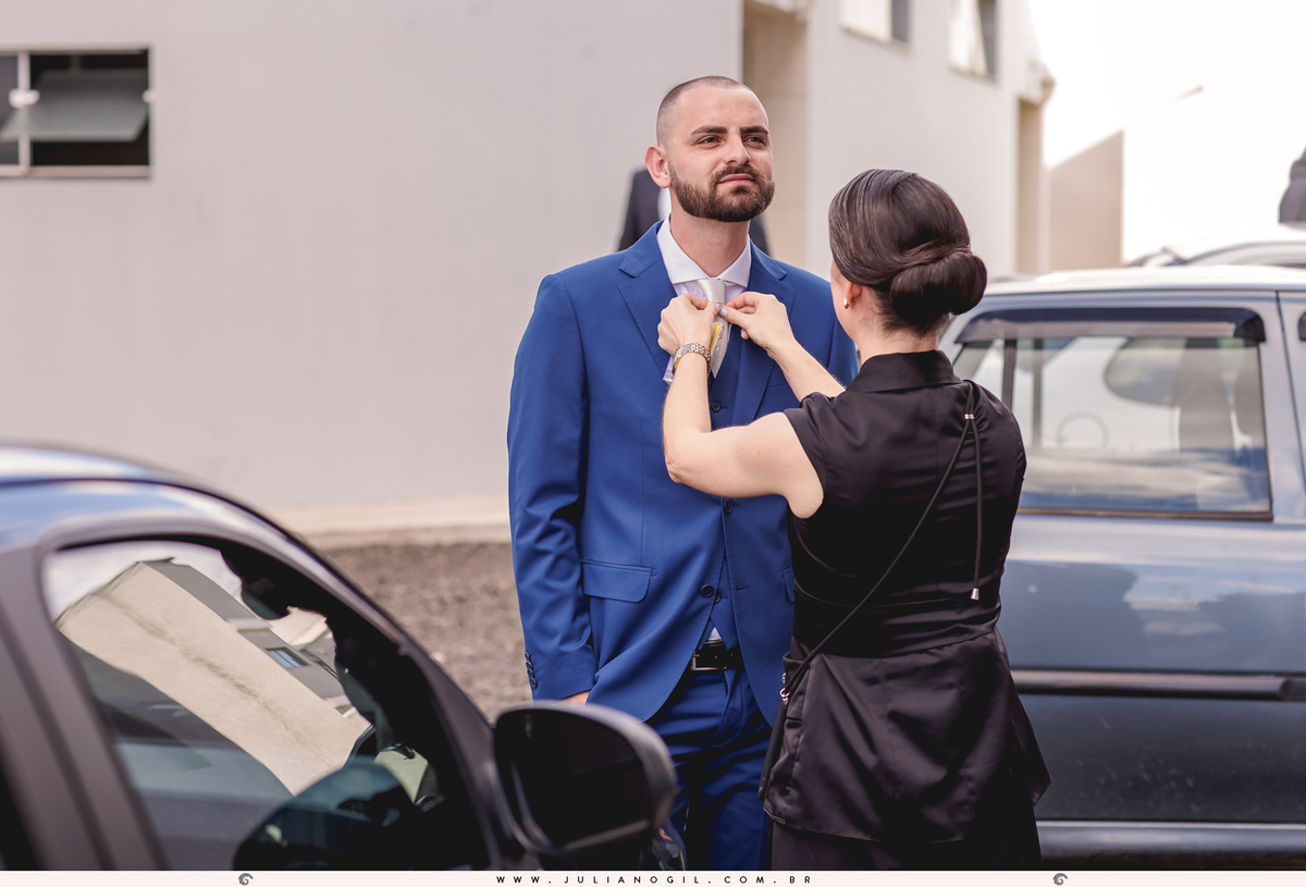 cerimonial arrumando a gravata do noivo em frente a igreja