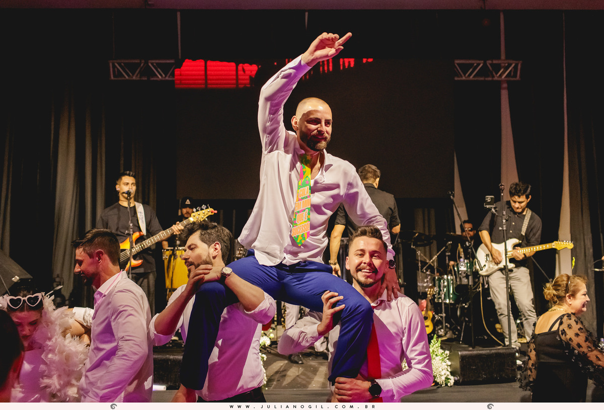 noivo sendo carregado por amigos durante a festa de casamento