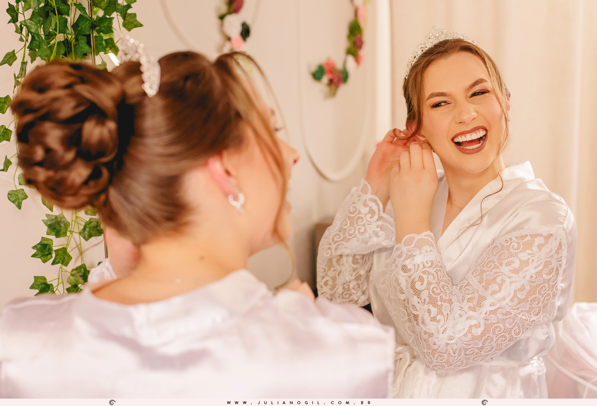 noiva Ana Elisa colocando o brinco e sorrindo no espelho durante o making of do casamento