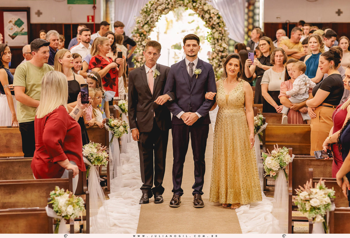 noivo entrando com os pais na cerimônia do casamento na igreja matriz em Rio Azul, Paraná