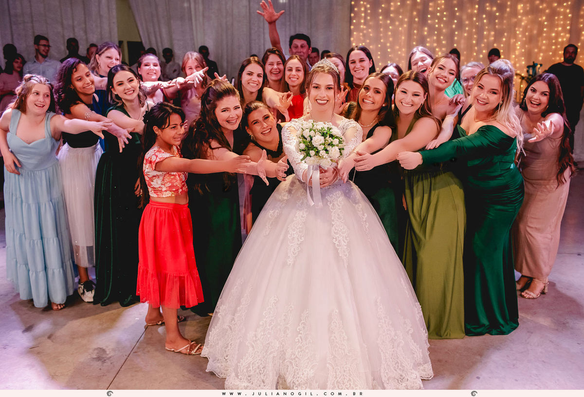 madrinha segunrando o buquê enquanto as convidadas tentam pegá-lo