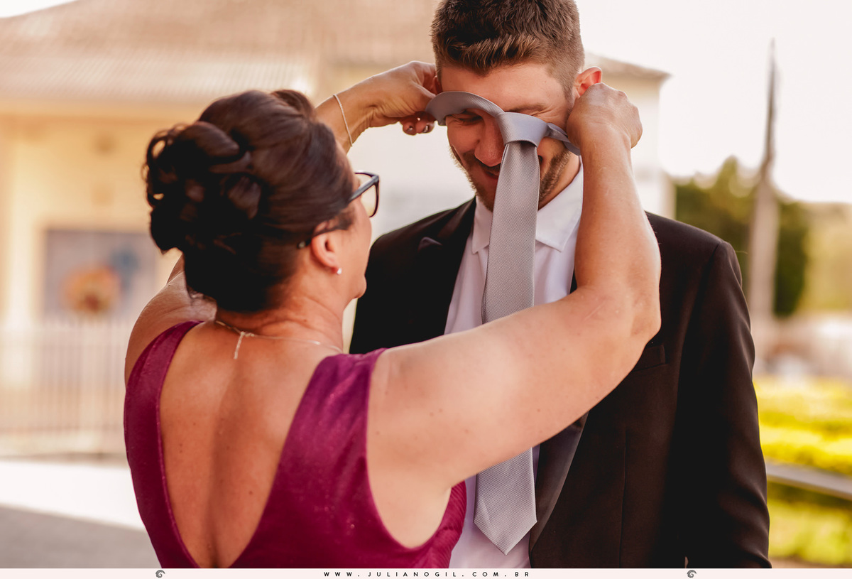 mãe colocando gravata no filho em frente a igreja casamento