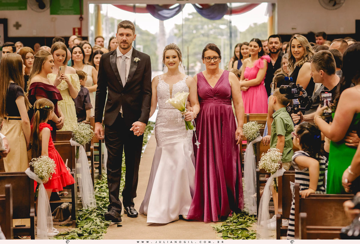 noiva entrando na igreja com o irmão e mãe no início da cerimônia