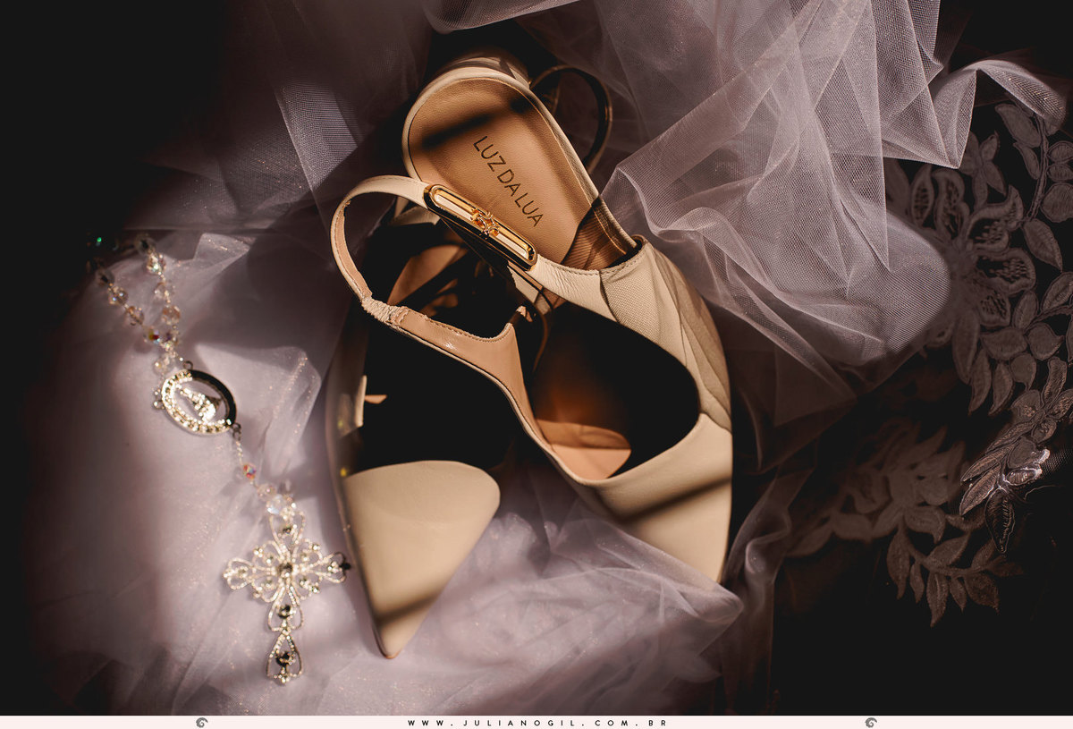 sapato da noiva sobre o véu e ao lado o crucifixo usado pela noiva