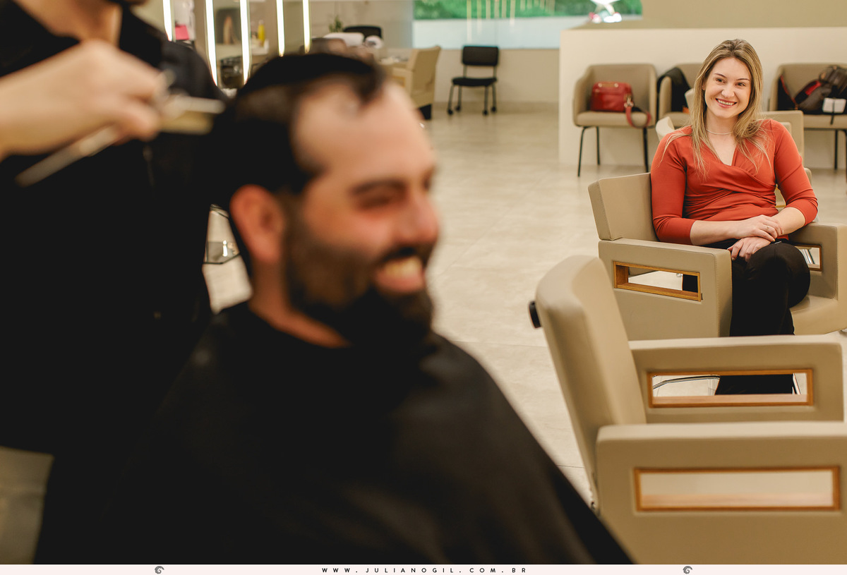 making of do noivo cortando o cabelo e a noiva ao fundo admirando