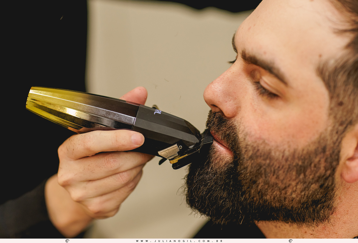 barbeiro cortando a barba do noivo com máquina