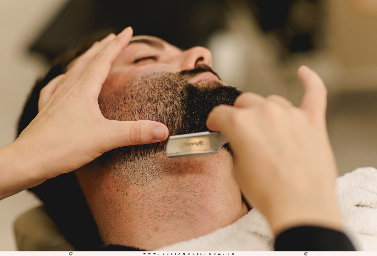 barbeiro com navalha cortando a barba do noivo próximo ao pescoço