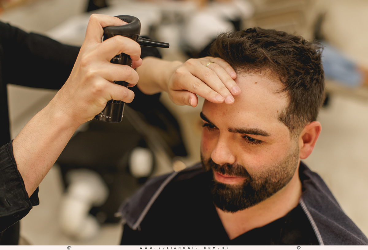barbeiro colocando spray e fazendo o topete do cabelo do noivo