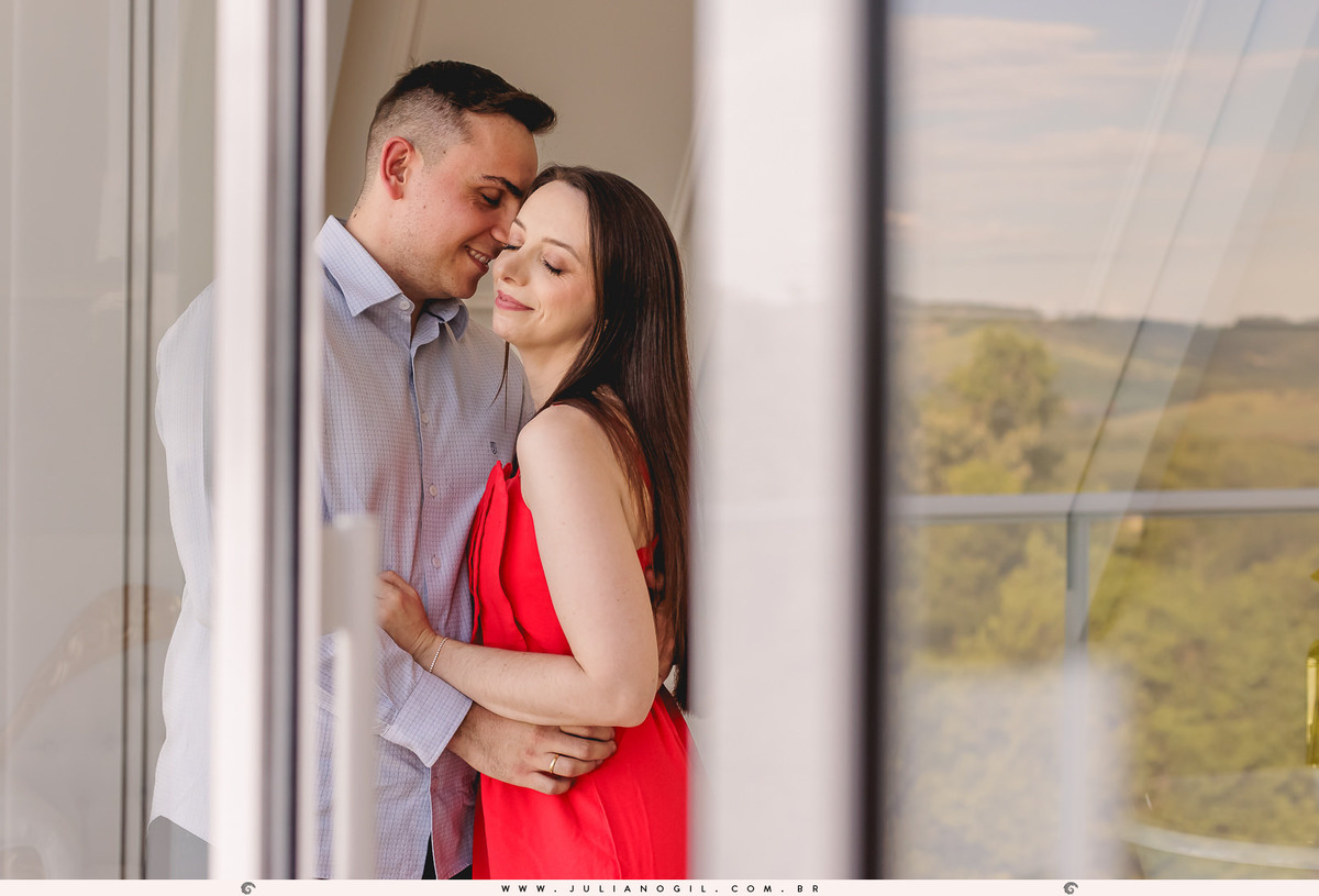 casal abraçados um de frente para o outro em frente a uma janela que aparece o canion no reflexo em Manoel Ribas-PR