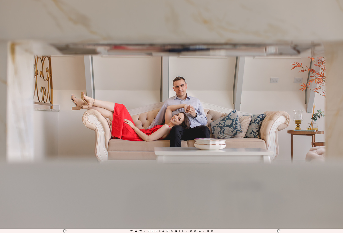 noiva deitada sobre o colo do noivo no sofá, a moldura da foto é feita pelo vão da parede da lareira