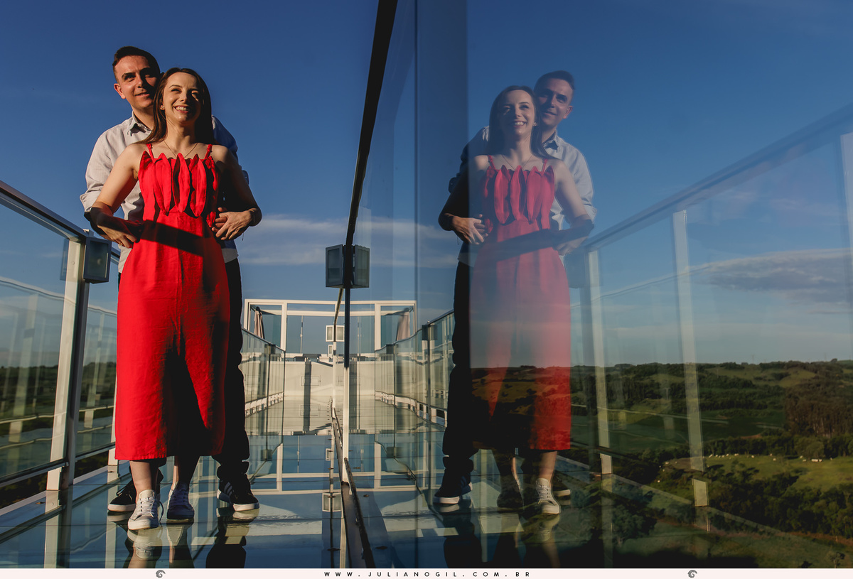 casal em uma plataforma do chalé em cima do canion em Manoel Ribas - PR com reflexo deles no vidro da ponte