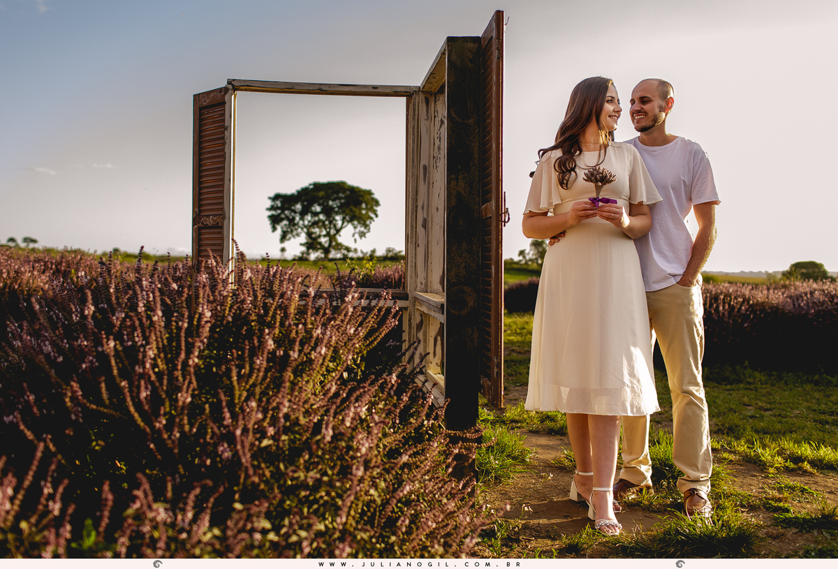 casal abraçados, noiva segurando um buquê de lavanda, e ao fundo uma janela que serve como moldura para a árvore que aparece ao fundo deles no lavandário dos sonhos em witmarsum no paraná