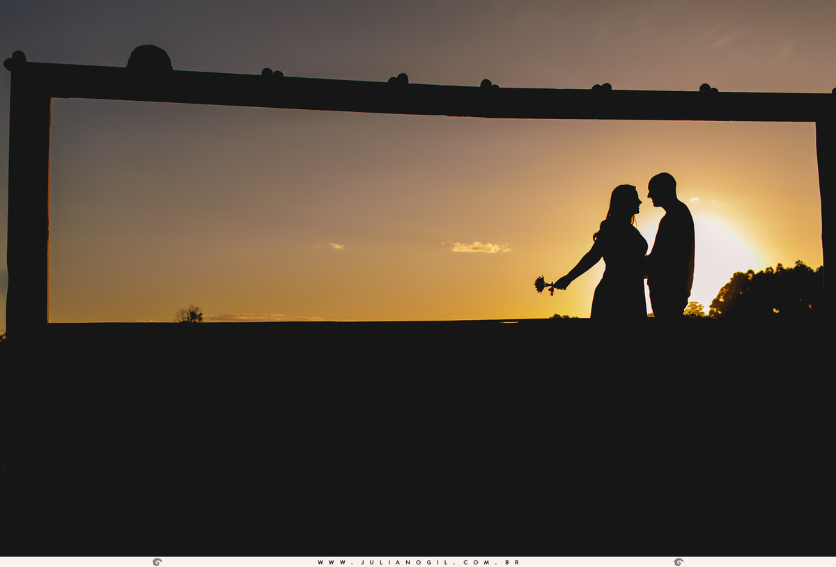 silhueta do casal no pôr do sol sendo emoldurada por estrutura de madeira