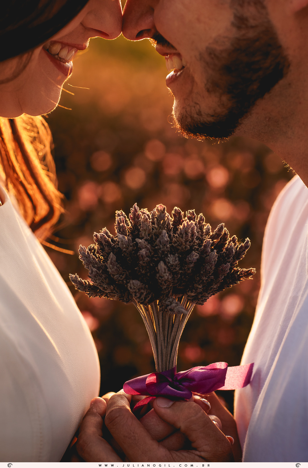 casal segurando juntos um buquê de lavanda no meio deles e sorrindo olhando um para o outro