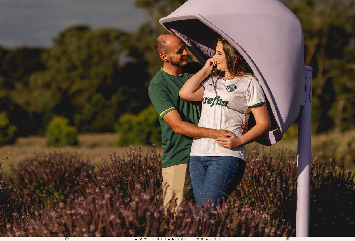 casal abraçados e encostados num orelhão de cor roxa no meio da plantação de manjericão no lavandário dos sonhos em witmarsum no paraná