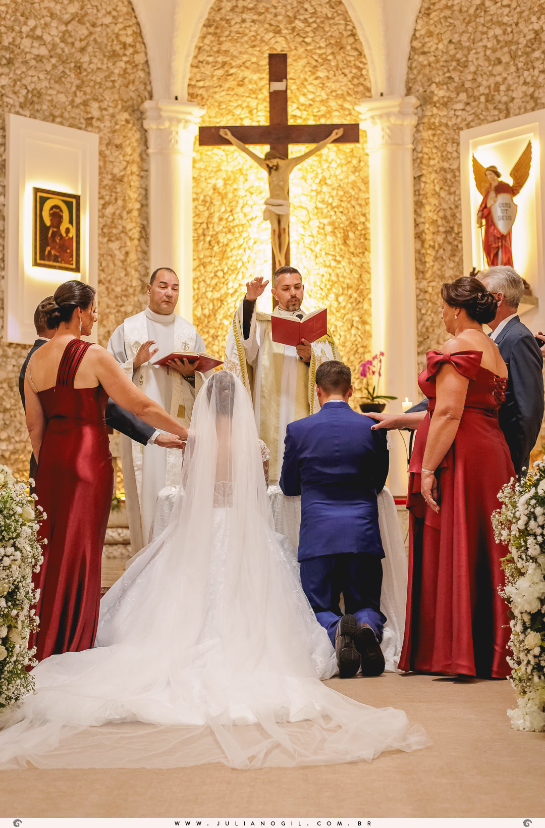 padre e pais dos noivos abençoando o casal no altar