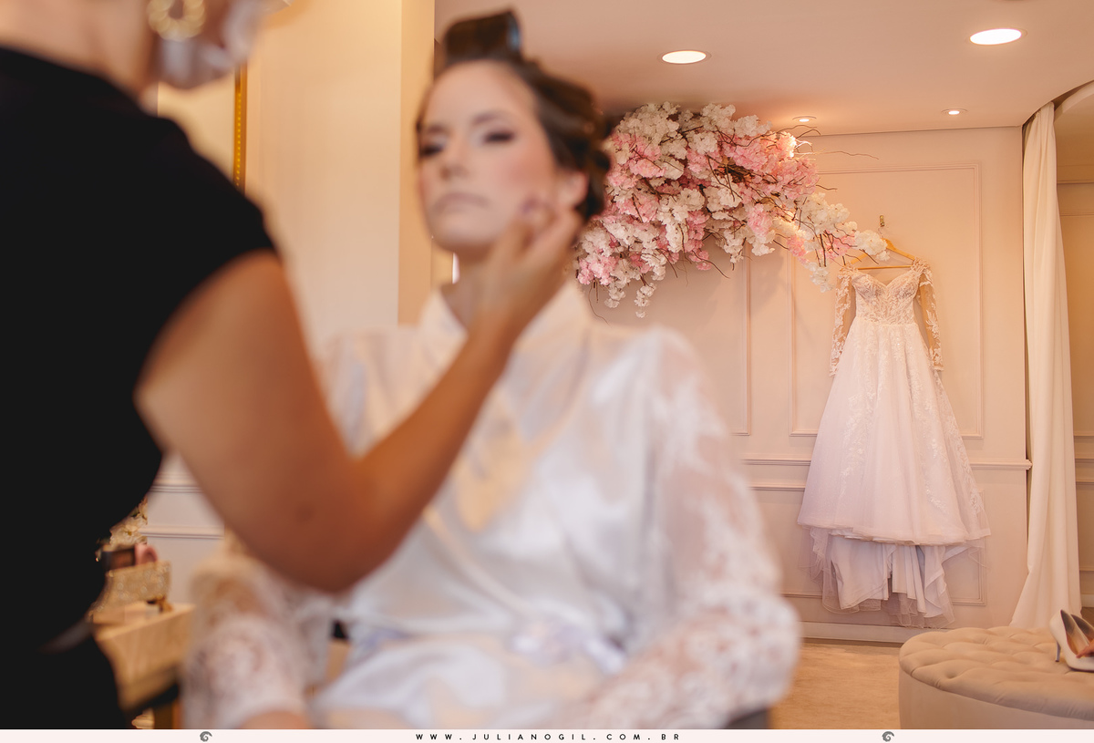 making of da noiva com vestido ao fundo e a noiva sendo maquiada em primeiro plano