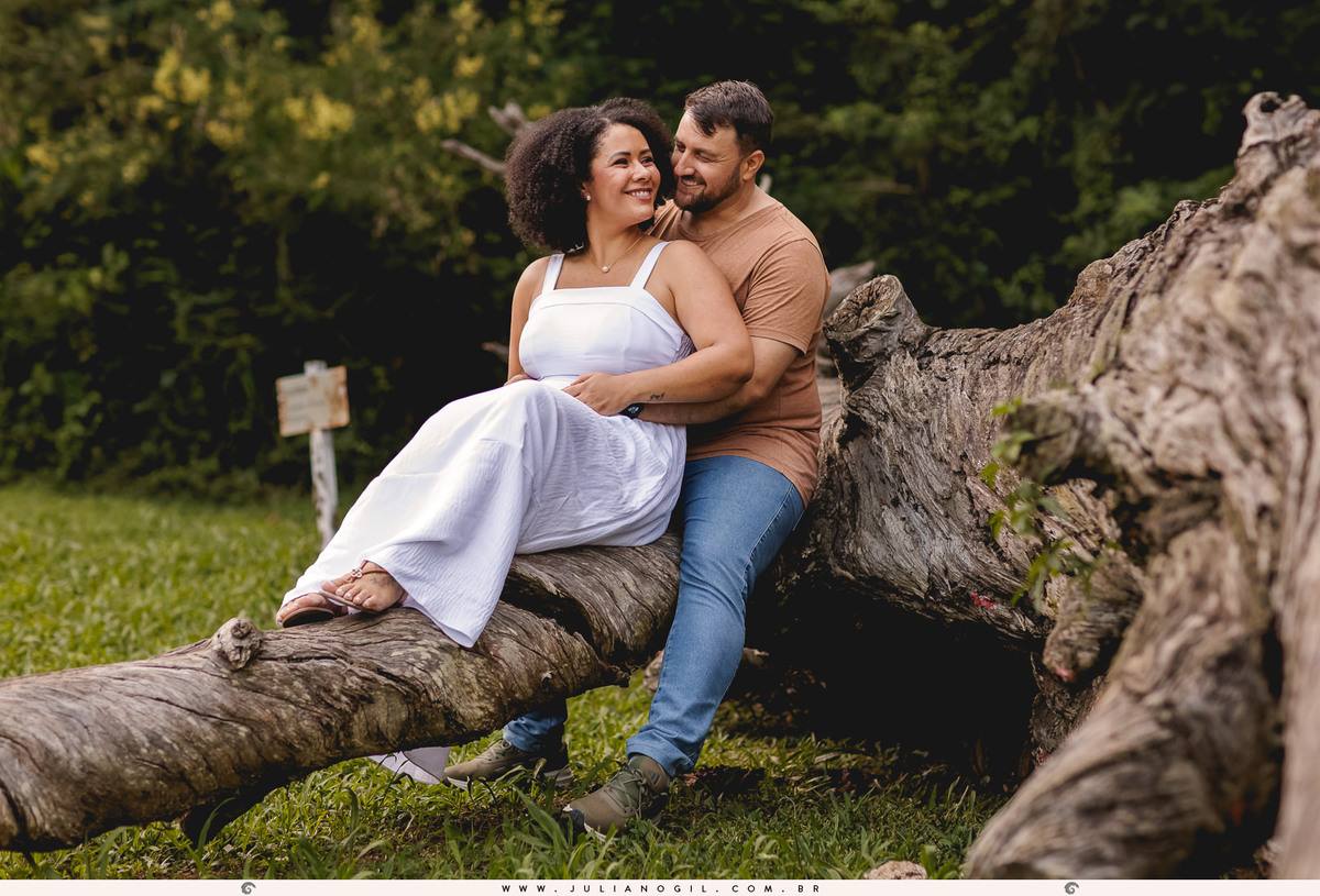 casal sentados se abraçando em cima de uma araucária caída na  na floresta nacional de irati