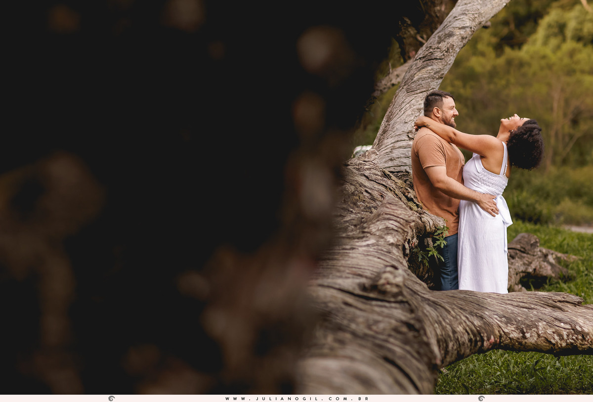 casal se abraçando encostados em uma araucária caída na floresta nacional de irati