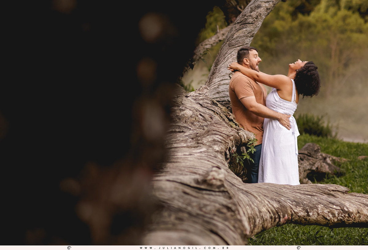 casal se abraçando encostados em uma araucária caída na floresta nacional de irati