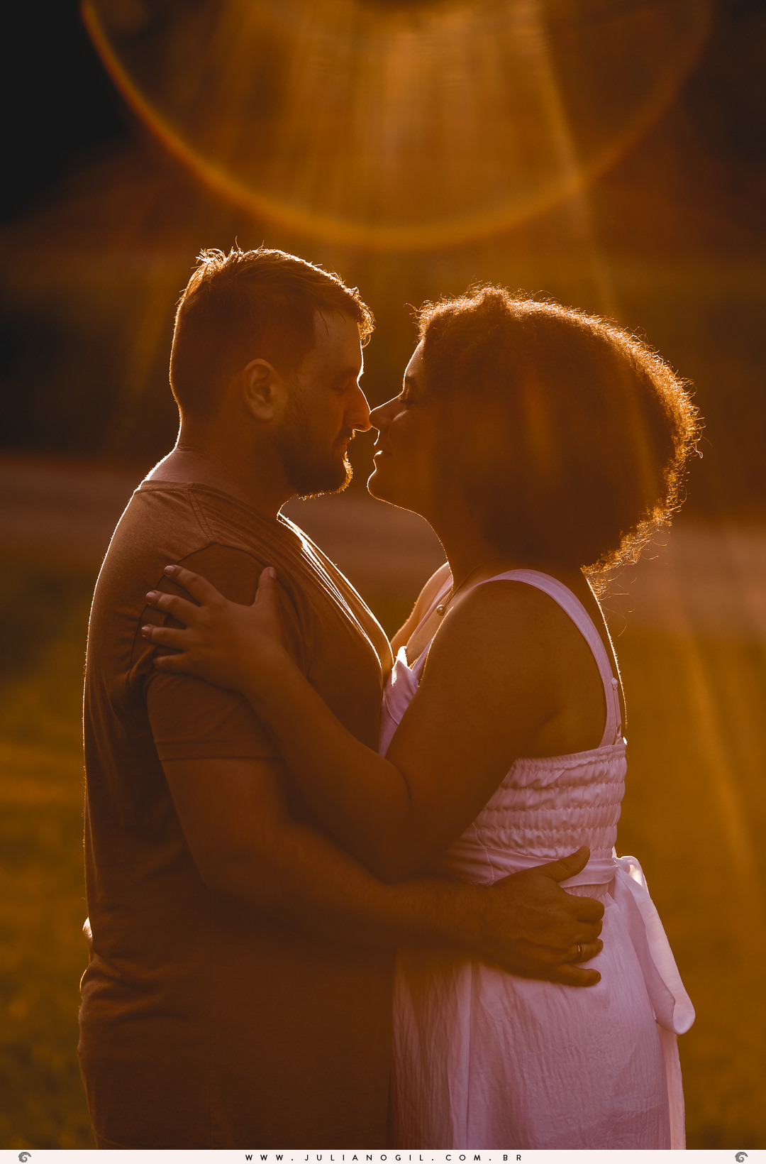 casal com o rosto bem próximos sento iluminados por uma luz do sol vinda de trás deles no pôr do sol  na floresta nacional de irati