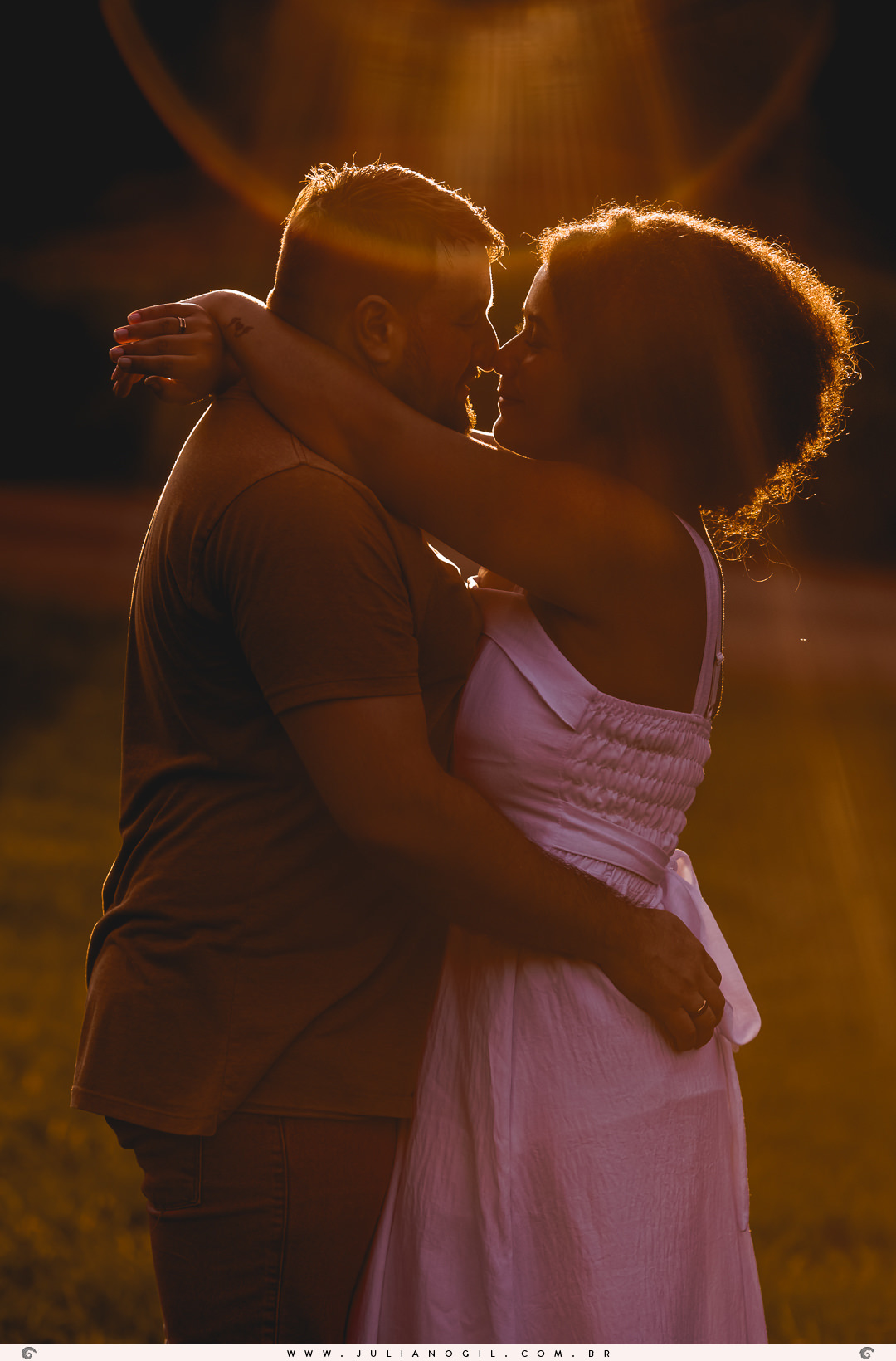 casal com o rosto bem próximos sento iluminados por uma luz do sol vinda de trás deles no pôr do sol  na floresta nacional de irati