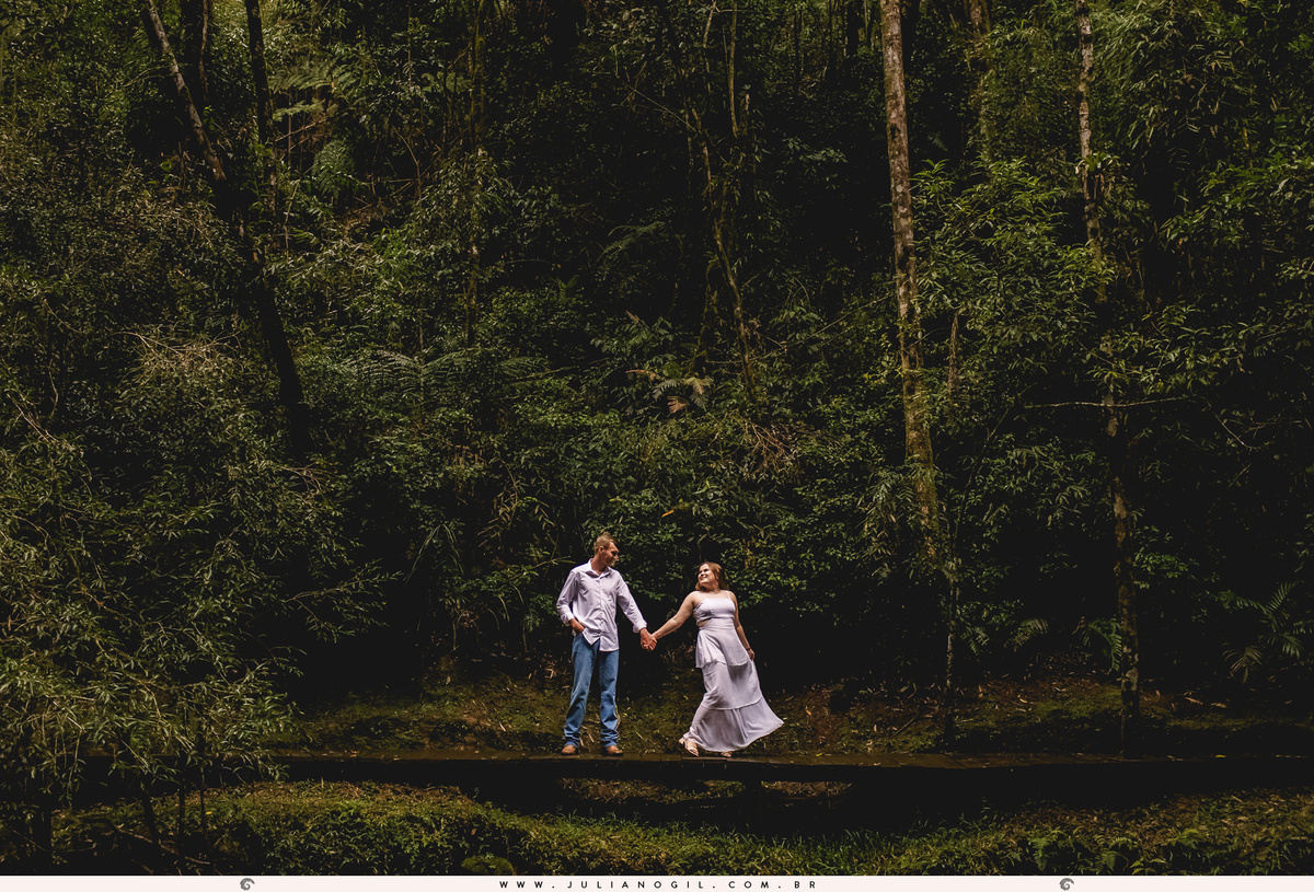 casal caminhando sob as pedras com a floresta ao fundo