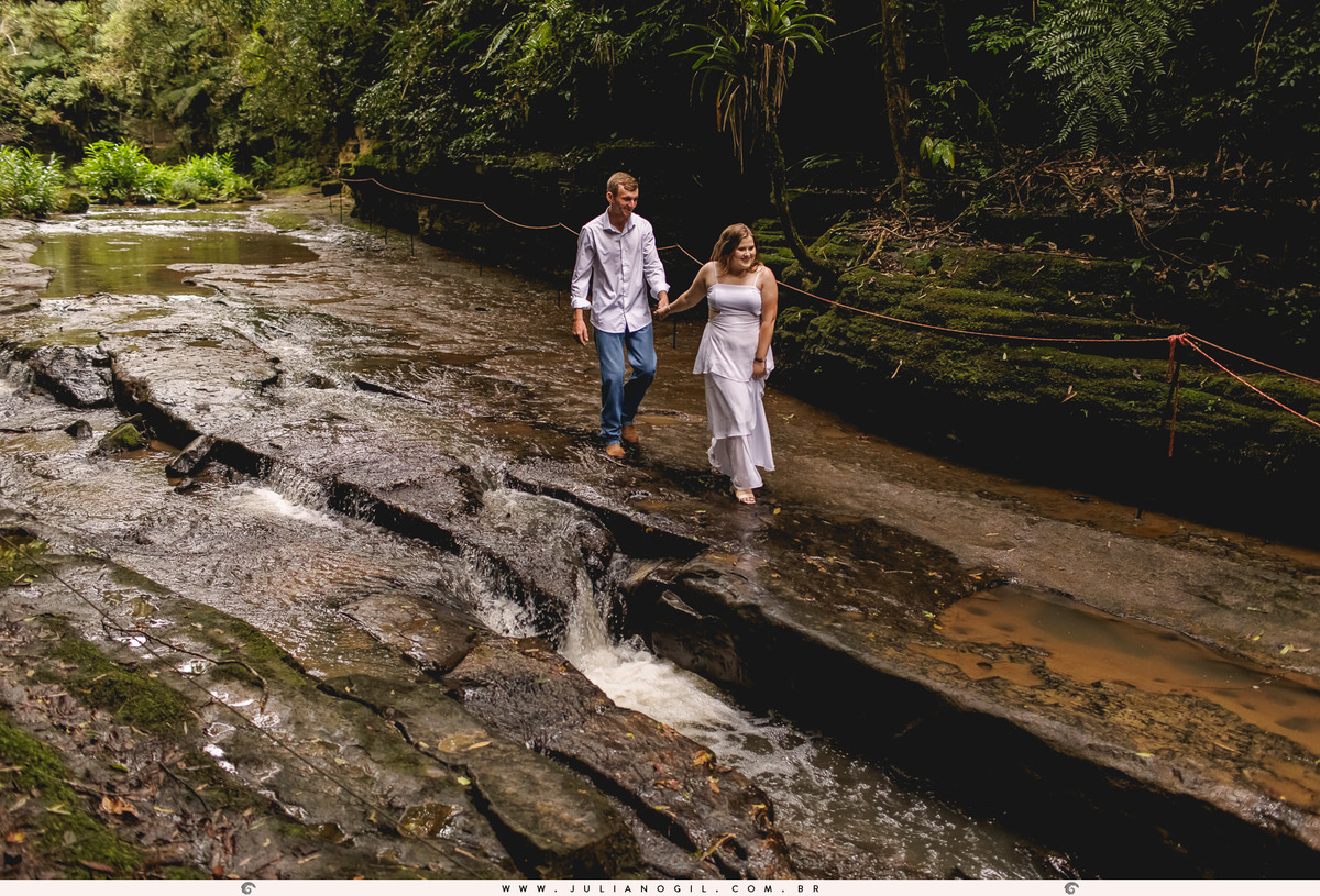 casal caminhando sobre as pedras de um pequeno riacho