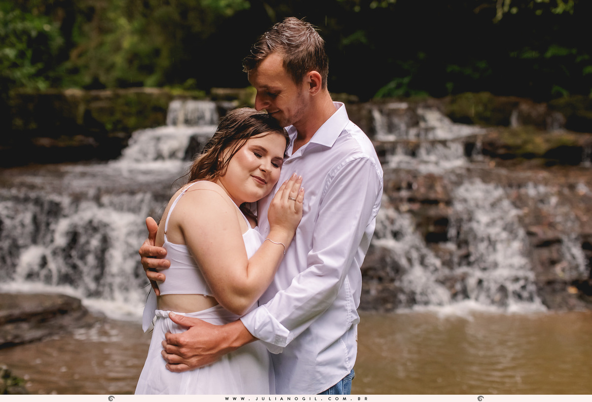 casal molhados abraçados em frente a cachoeira