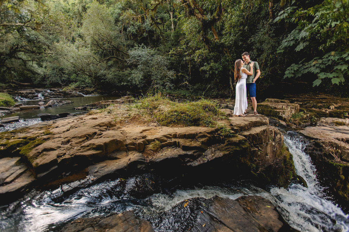 plano inicial as pedras da cachoeira e ao fundo o casal abraçados