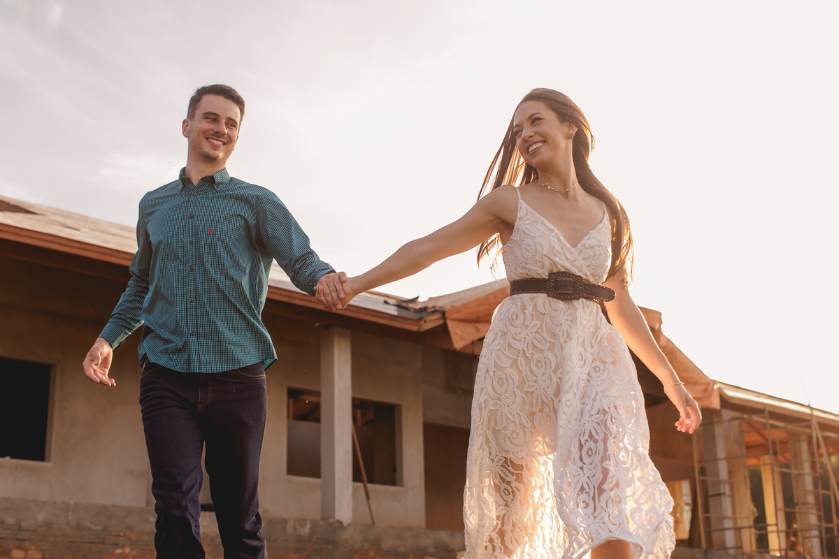 casal correndo em frente a casa em construção