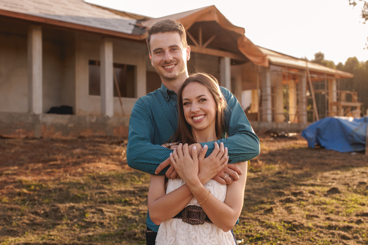casal abraçados em frente a casa em construção